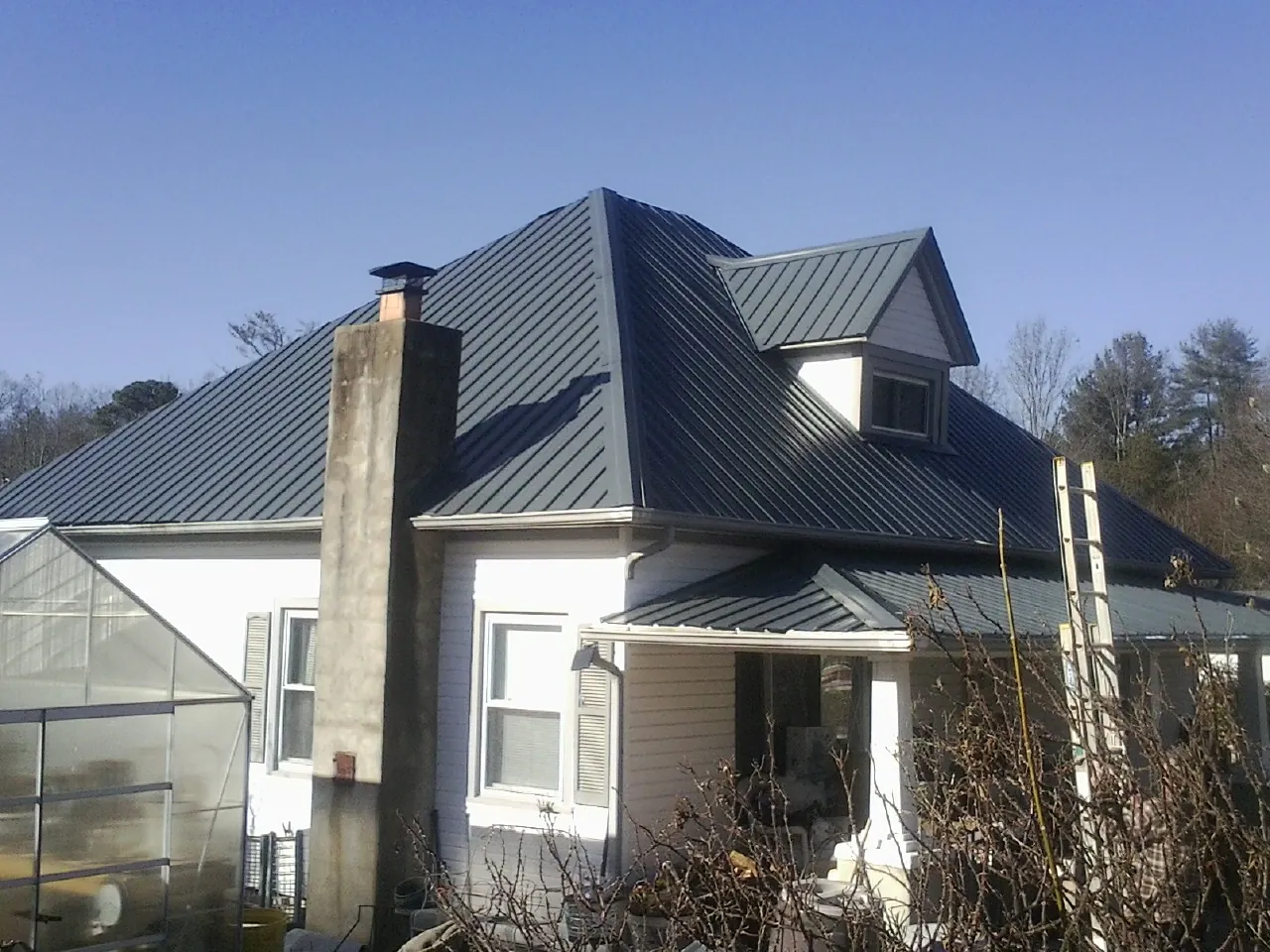 Dark blue standing seam metal roof on a white farmhouse with dormer — Slate & Tile Roof Repair by Roofing Brothers in Palos Heights