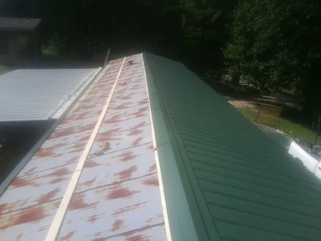 Old rusted panels beside newly installed green metal roofing — Wind Damage Roof Repair by Roofing Brothers in Palos Heights