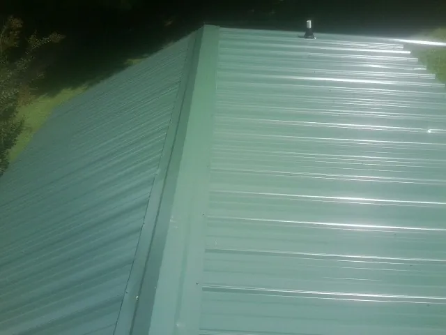 New green metal panels meeting at the ridge of a roof — Flat Roof Repair work by our crew in Palos Heights