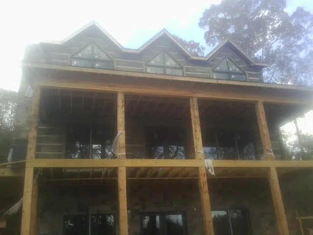 Dormers and porch framing on a large log home under construction — Roof Coating work by our crew in Palos Heights