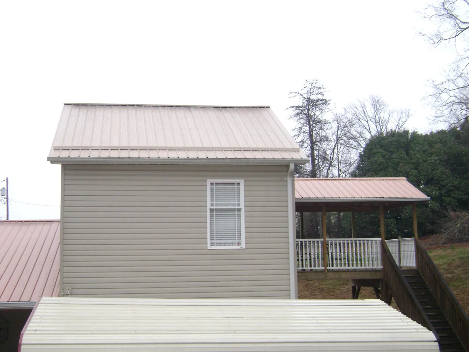 Tan metal roofs on a two story addition and attached porch, from a Roof Replacement job in Palos Heights
