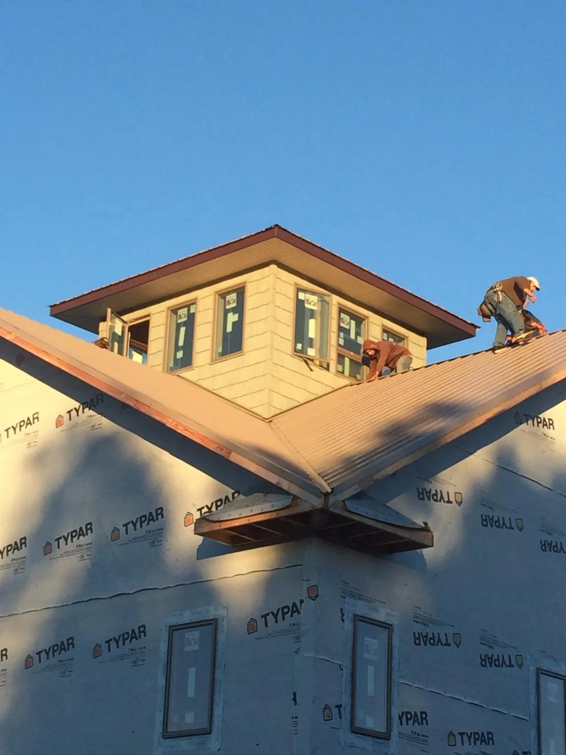 Roofers working around a rooftop cupola on a new metal roof at sunset — Roof Waterproofing in Palos Heights by Roofing Brothers